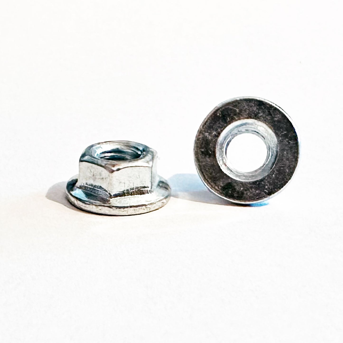 A white M5 plain flanged nut with a trivalent coating on a plain background. M5 Plain Flanged Nut Trivalent White 8mmA/F JIS 92015-1259