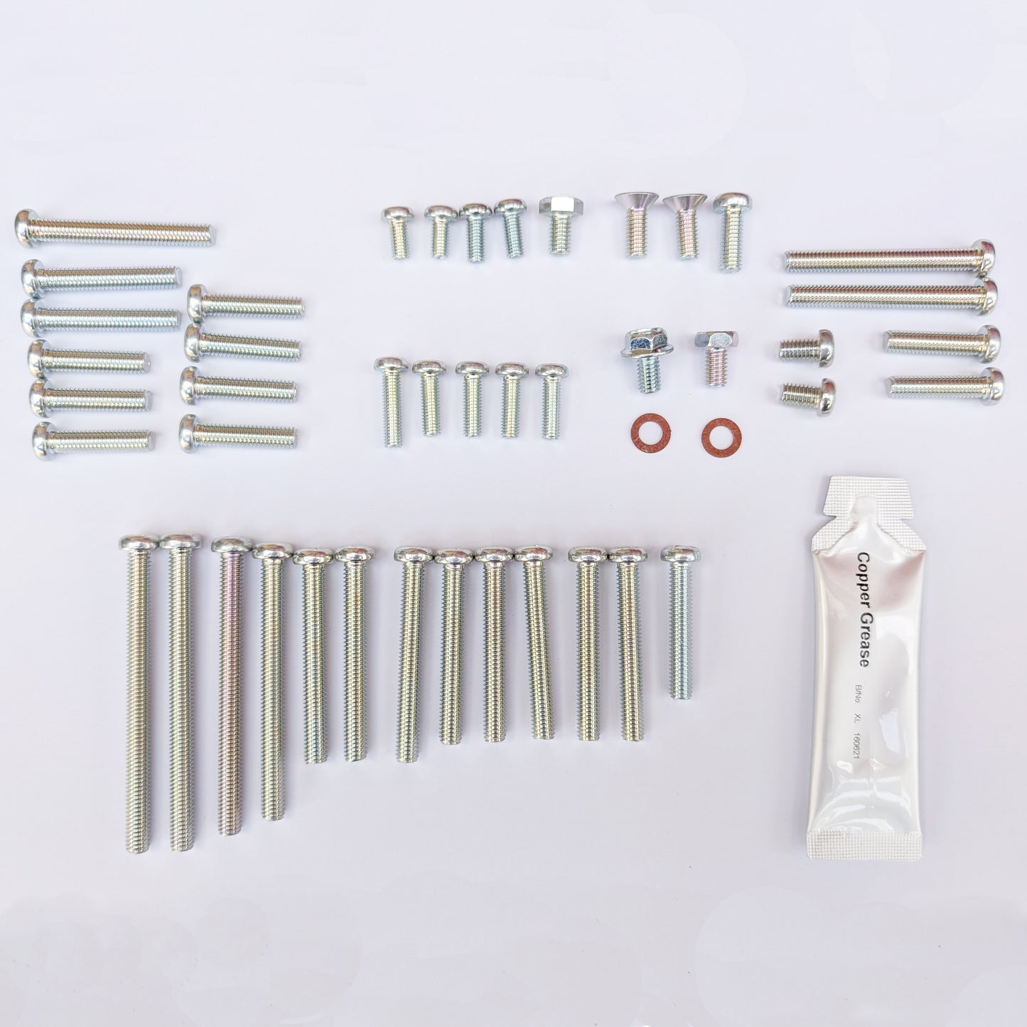 Collection of screws, bolts, washers, and a tube of grease on a white background