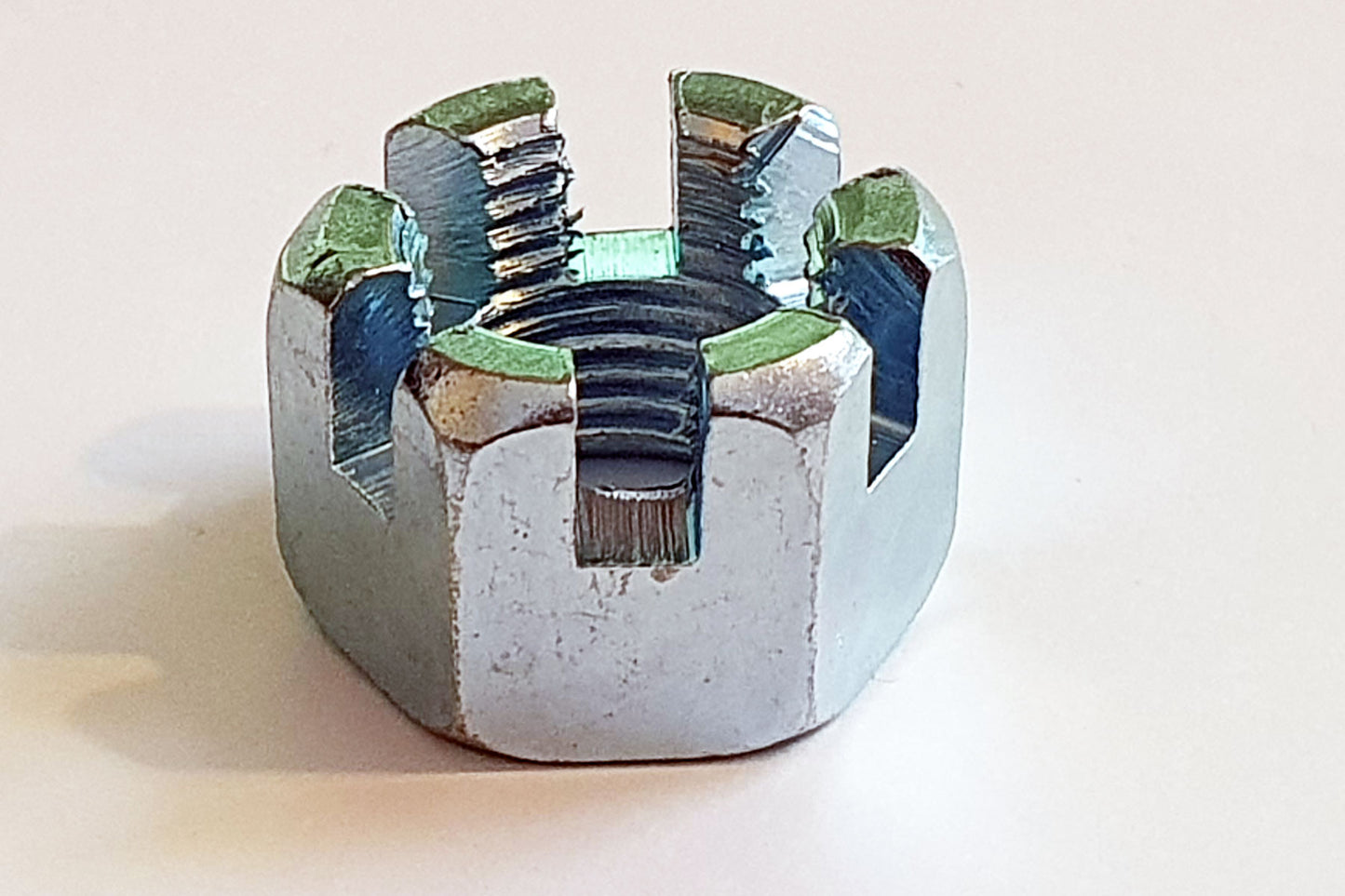 A silver-colored M16-1.50 fine pitch castle nut made of zinc with visible threads and slot.