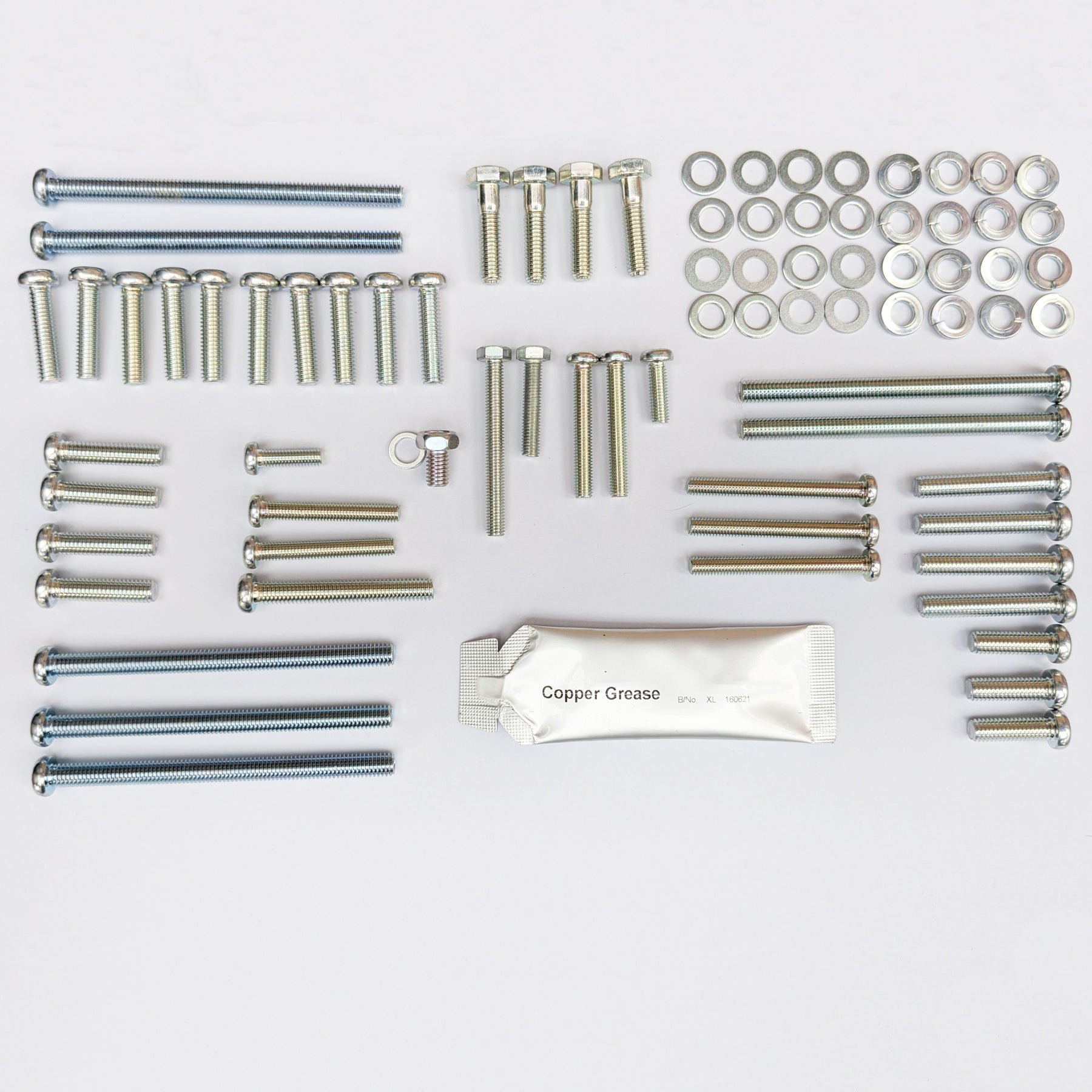 Collection of metal screws, bolts, and washers on a white background with a packet of copper grease. made into screw kit to fit a Suzuki GT380 from 1972 to 1977