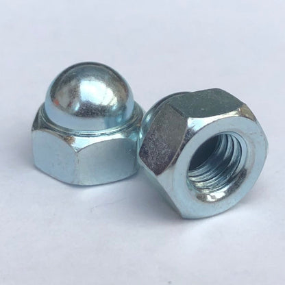 Two trivalent white domed nuts with a visible threaded interior, placed on a clear surface. M5 Dome Nut Low Top Trivalent White 8mmA/F JIS 92015-3802